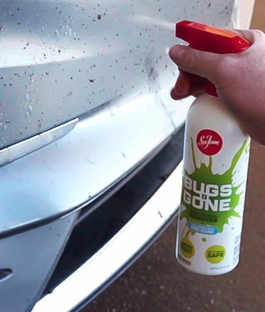auto owner spraying the front of a bug-covered car grill with Bugs B Gone 16 oz Spray bottle
