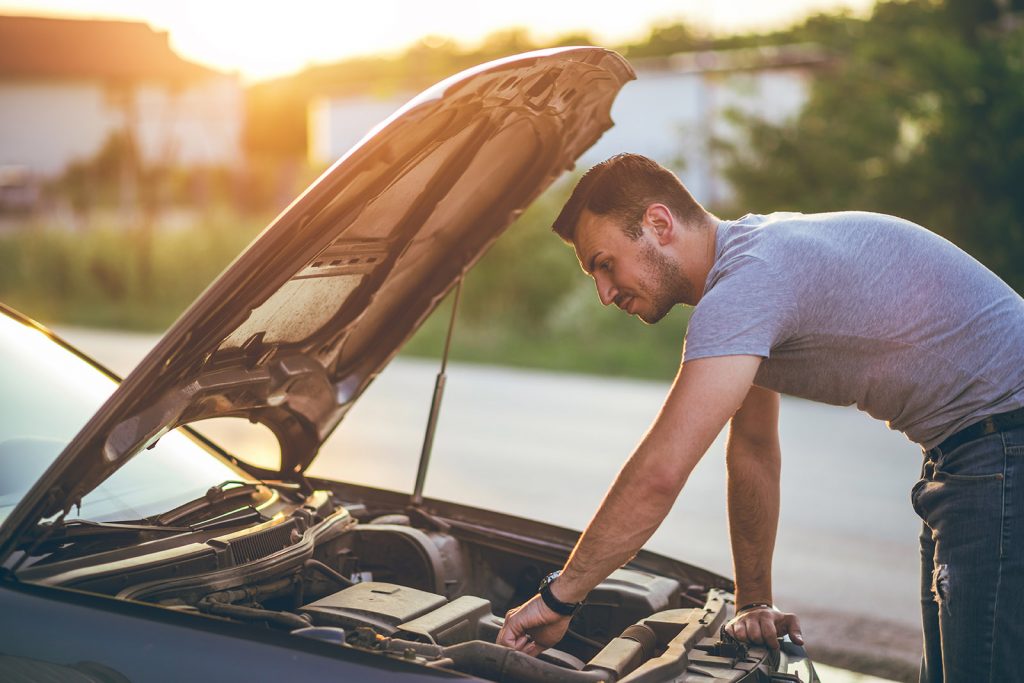 Young man repairing car on the side of the road